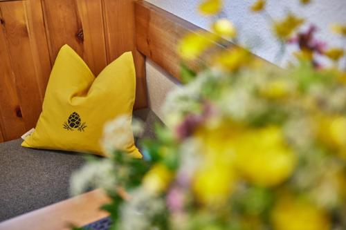 a yellow pillow sitting on a bench with flowers at Gästehaus Sonnenheim in Mittenwald