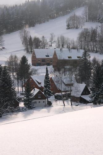a house covered in snow with trees and houses at Apartmán u sjezdovky Filipovice in Filipovice