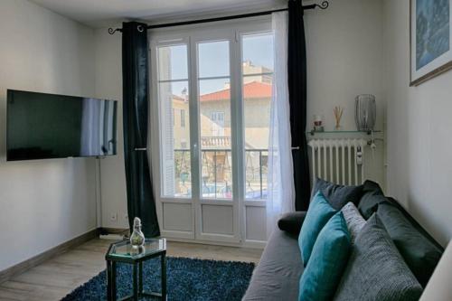 salon z kanapą i przesuwnymi szklanymi drzwiami w obiekcie Charme et Confort pour vos vacances sur Nice w Nicei