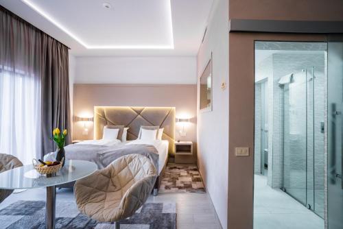um quarto de hotel com uma cama, uma mesa e uma porta de vidro em Hotel Eden Garden Spa em Câmpulung Moldovenesc