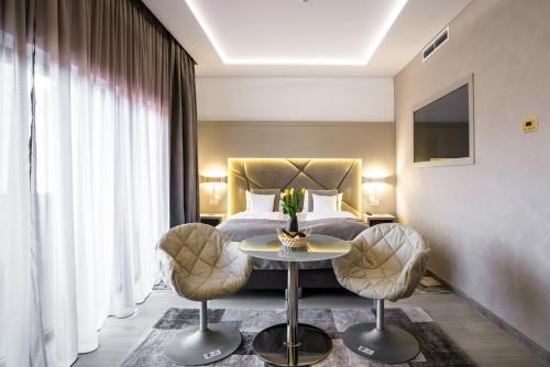 a hotel room with a bed and a table and chairs at Hotel Eden Garden Spa in Câmpulung Moldovenesc