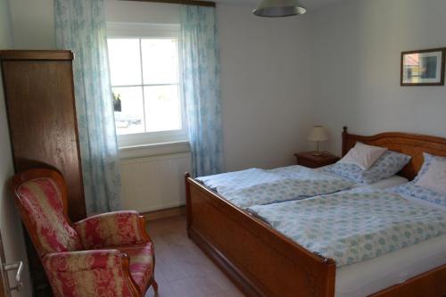 a bedroom with a bed and a chair and a window at Ferienhaus Bayerwald in Ringelai