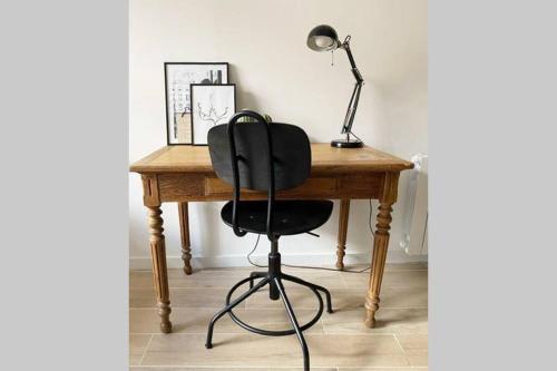 Un escritorio con una silla negra y una lámpara. en Le Clémenceau, en Hyères