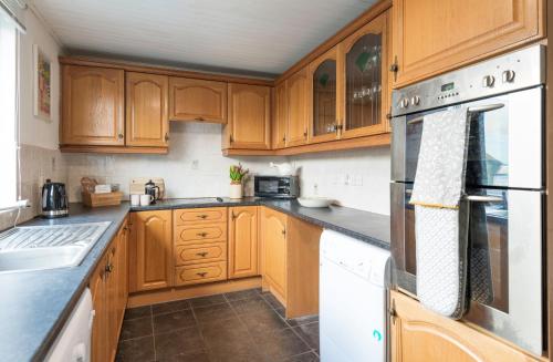 a kitchen with wooden cabinets and white appliances at Potters Retreat in Alnwick