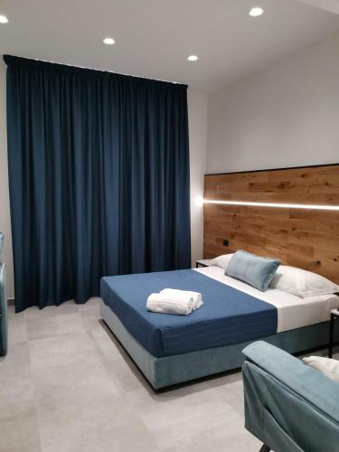 a bedroom with a large bed with a blue blanket at Hotel Portum in Giardini Naxos