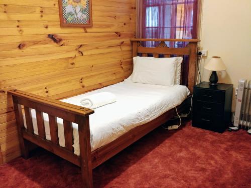 a bedroom with a bed with a wooden wall at Historic cottage 200m from shops and cafes Wifi Netflix included - #142 in Bathurst