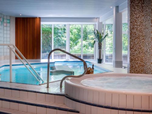 una bañera de hidromasaje en una habitación de hotel con piscina en Les Appartements du Parc - Accès piscine et spa, en Munster