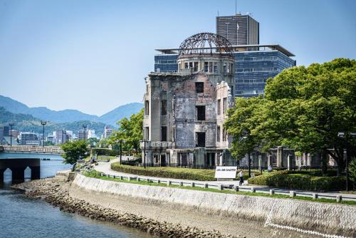 an old building next to a river with a bridge at Cocostay The Peace Memorial Park ココステイ平和記念公園 Excellent location overlooking Peace Park! in Hiroshima