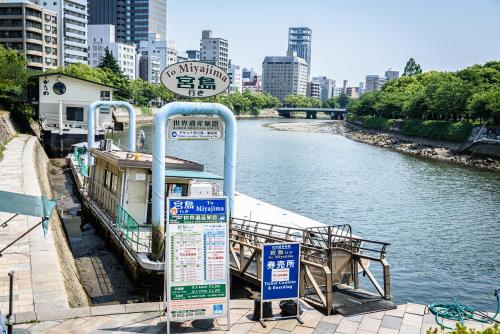 a bus stop next to a river with a boat at Cocostay The Peace Memorial Park ココステイ平和記念公園 Excellent location overlooking Peace Park! in Hiroshima