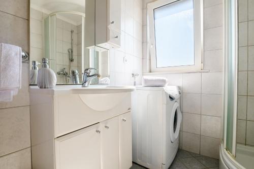 a white bathroom with a sink and a washing machine at Villa Rustica in Neum