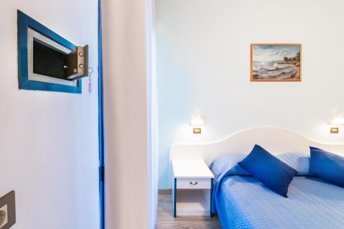 a bedroom with a bed with blue pillows and a tv at Hotel Tivoli in Misano Adriatico