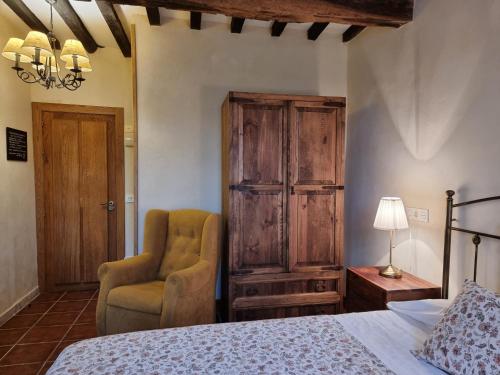 a bedroom with a bed and a chair and a lamp at Posada Condado de la Mota in Mogro