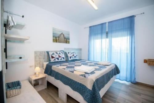 Schlafzimmer mit einem Bett mit einer blauen und weißen Bettdecke in der Unterkunft Antonia Apartment Marina Surf Residence in Mamaia Nord – Năvodari