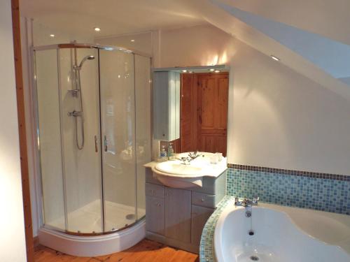 a bathroom with a shower and a tub and a sink at Poet's Cottage in Trefriw