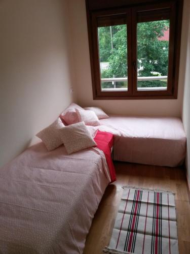 two beds in a room with a window at En el Sella in Cangas de Onís