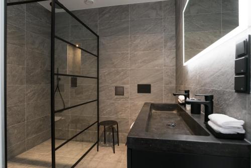 a bathroom with a sink and a glass shower at Midtown Hotel Rotterdam in Rotterdam