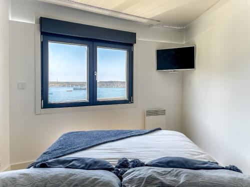a bedroom with a bed with a window and a tv at Apartamento Dique Guardes in A Guarda