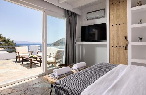 1 dormitorio con 1 cama y balcón con vistas. en Cinco Suites, en Kithnos