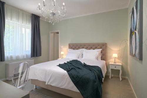 een slaapkamer met een groot wit bed met een kroonluchter bij Holiday Home Plasa in Žrnovnica