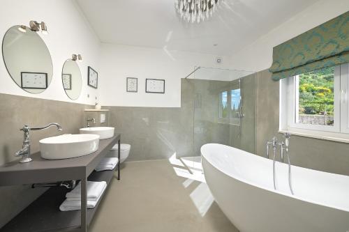 een badkamer met 2 wastafels, een bad en spiegels bij Holiday Home Plasa in Žrnovnica