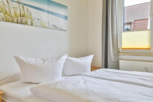 Una cama blanca con almohadas blancas y una ventana. en Apartment Diana mit Terrasse, en Zempin