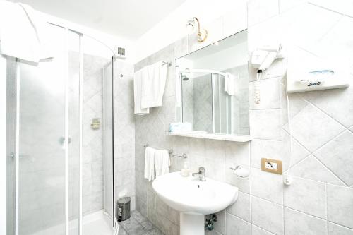 a white bathroom with a sink and a shower at Hotel Fontana in Amalfi