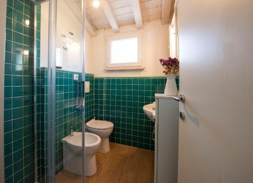 a green tiled bathroom with a toilet and a window at 99 Via Esino in Ancona