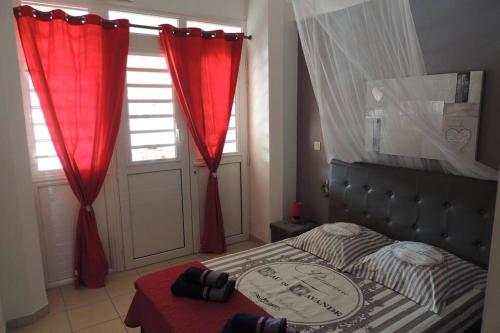 a bedroom with a bed with red curtains and a window at Séjour de rêve en Martinique 6 pers avec piscine in Les Trois-Îlets