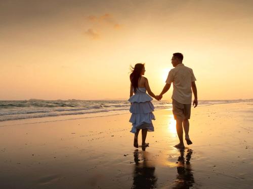 a man and a woman walking on the beach at Novotel Rayong Rim Pae Resort in Klaeng