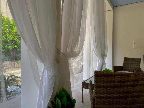 a living room with white curtains and a table and chair at Casa Mar - B&B - in Terracina