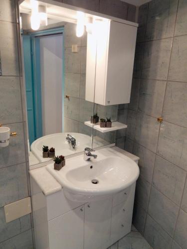 a white bathroom with a sink and a mirror at Apartments Igor in Piran