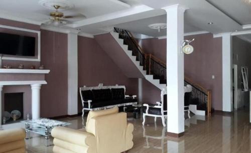 a living room with a staircase and a piano at Hotel Graha Soeltan in Sunggal