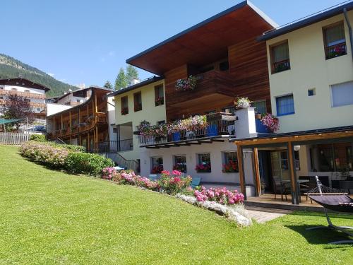 ein Gebäude mit Blumen auf den Balkonen in der Unterkunft Garni Enrosadira in Vigo di Fassa