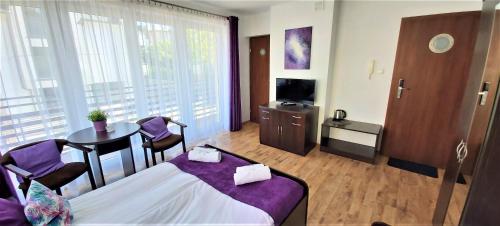a room with a bed and a table and a tv at Villa Magna in Gdynia
