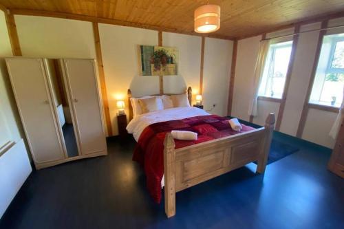 um quarto com uma cama de madeira num quarto com janelas em The Cosy Cabin em Swinford