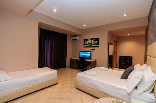 a hotel room with two beds and a television at Aliko Hotel in Vlorë