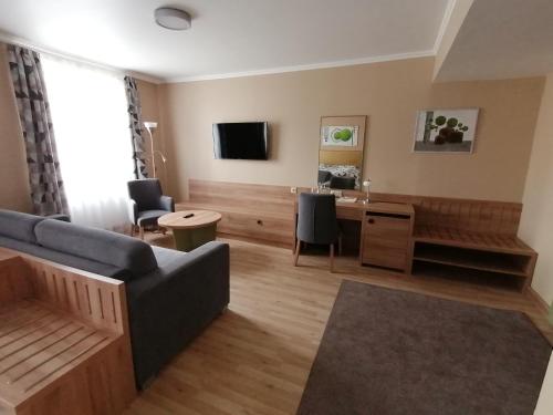 a living room with a couch and a desk at Arany Bárány Hotel in Zalaegerszeg