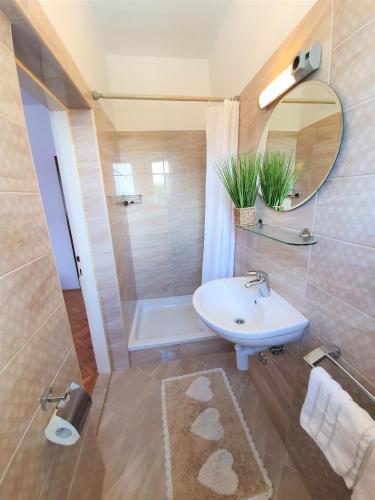 a bathroom with a sink and a mirror and a tub at Apartments Angela in Kampor