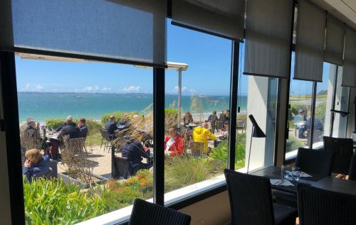 a view of the ocean from a restaurant window at Logis Hôtel & Restaurant LES MOUETTES - Larmor Plage, Proche de LORIENT in Larmor-Plage