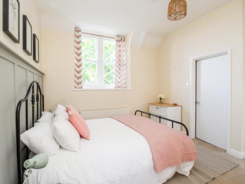 a bedroom with a white bed with pink pillows at Sea Pink Cottage in Swanage