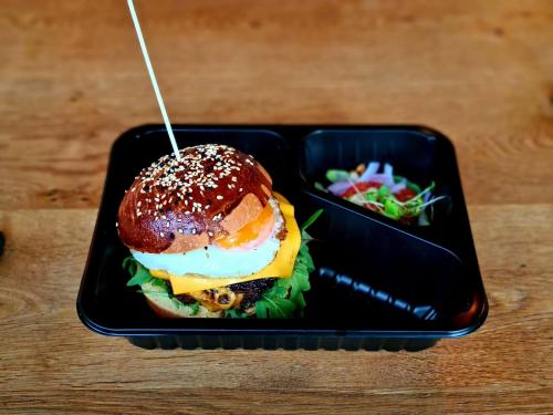 a black tray with a hamburger and a salad at Blue Mandarin Marina in Gdańsk