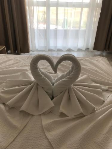 Dos cisnes haciendo un corazón en una cama en Apart Allure Dobi en Primorsko