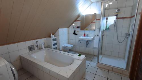 a bathroom with a tub and a shower and a sink at Ferienwohnung Uchte in Uchte