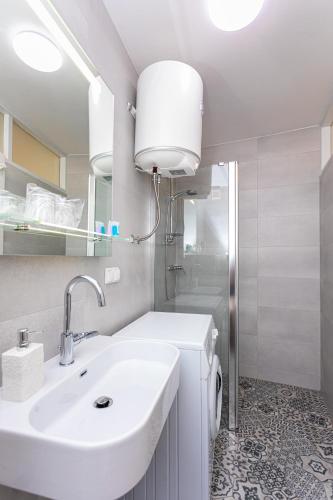 a white bathroom with a sink and a mirror at Apartment Jano in Baška