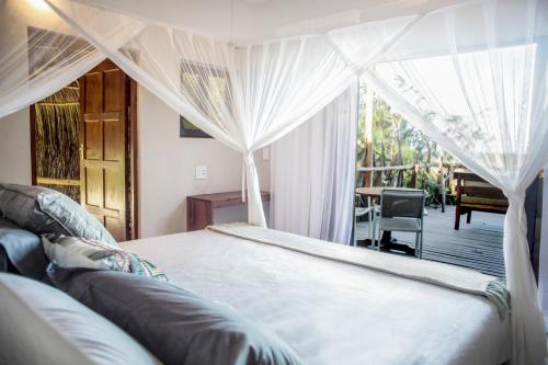 a bedroom with a bed with curtains and a table at Tofinho Beach House Apartments in Inhambane