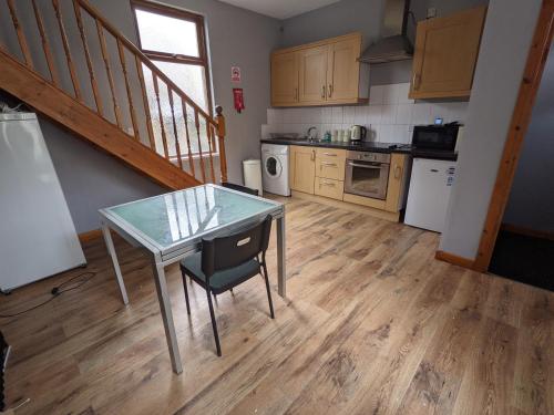 a kitchen with a glass table and a staircase at Cheap and Cosy Rooms with TV in Clayton le Moors
