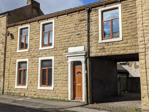 an old brick building with a door and a garage at Cheap and Cosy Rooms with TV in Clayton le Moors