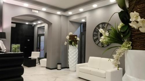a lobby with white furniture and a clock on the wall at Sweet Central Hotel in Caserta