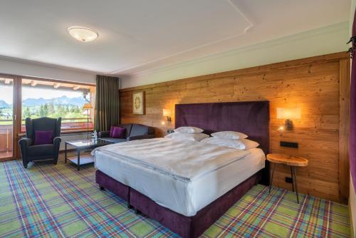 a hotel room with a large bed and a balcony at Relais & Châteaux Gut Steinbach Hotel Chalets SPA in Reit im Winkl