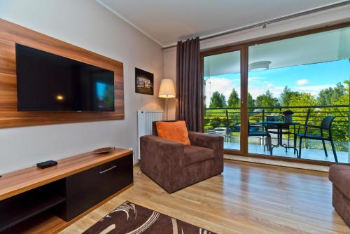 a living room with a flat screen tv and a chair at BlueApart Apartamenty Na Klifie in Władysławowo